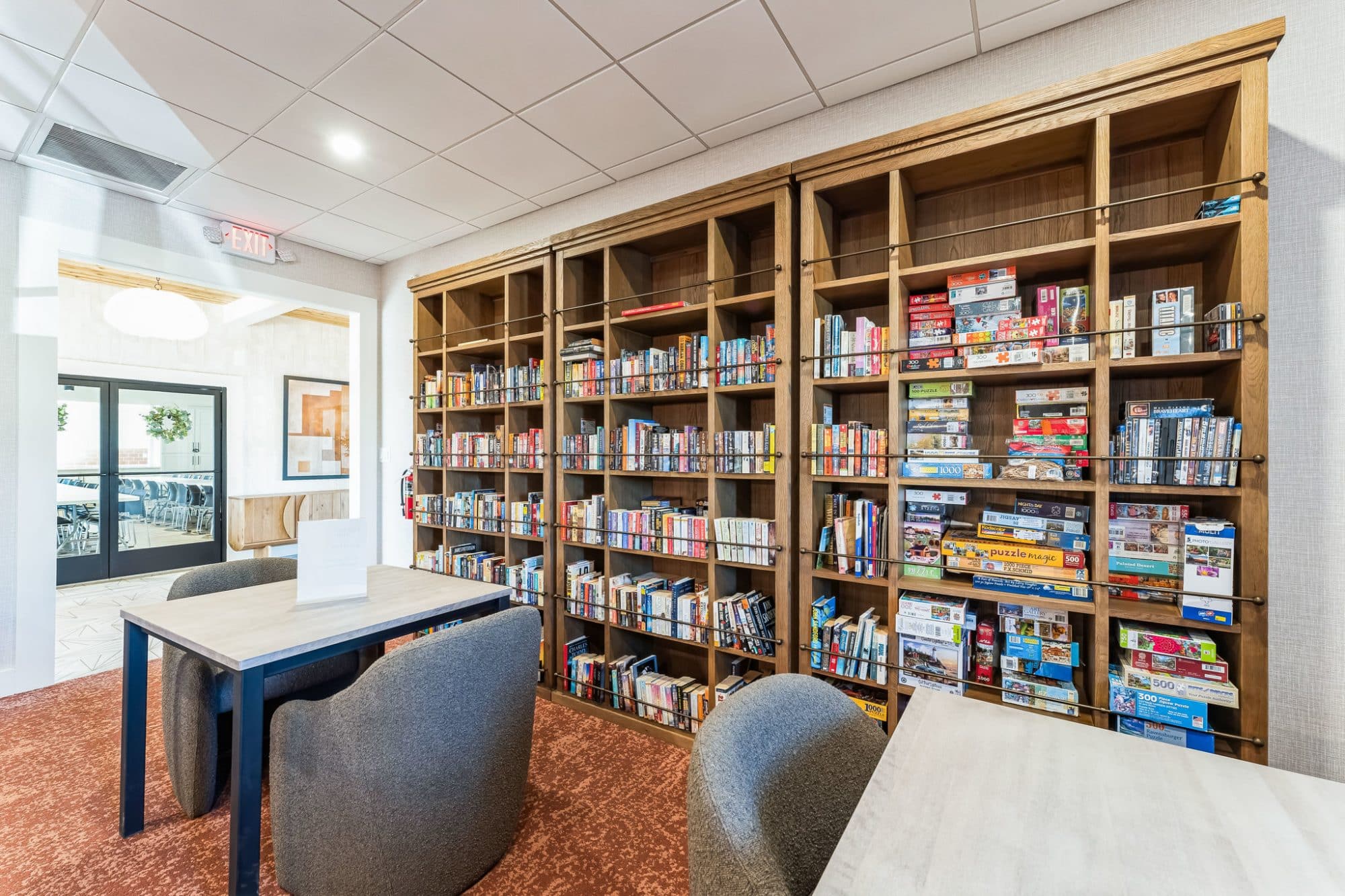 Cozy library and game room with bookshelves filled with books and board games, seating areas, and warm lighting near Mesa, AZ