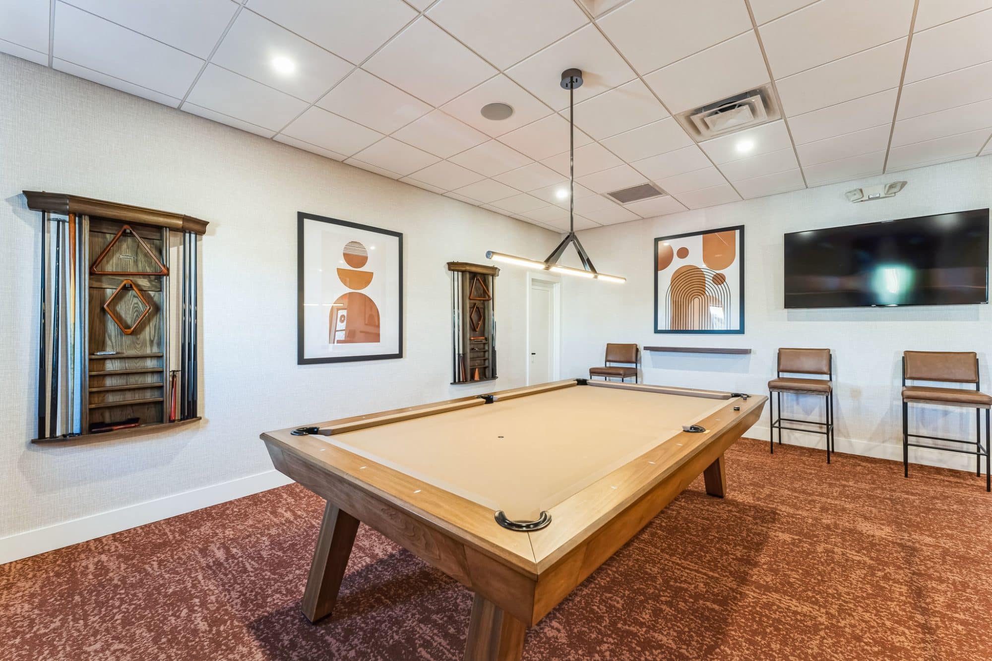 Modern game room with a pool table, cue rack, framed artwork, and a wall-mounted TV near Phoenix