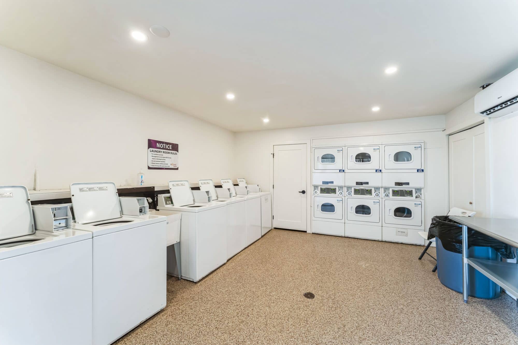 Laundry room with multiple washers and dryers, a folding table, and bright lighting in apache junction az